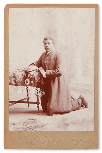 (RELIGION.) AMERICAN WEST. Large cabinet card photograph of a kneeling African American priest.